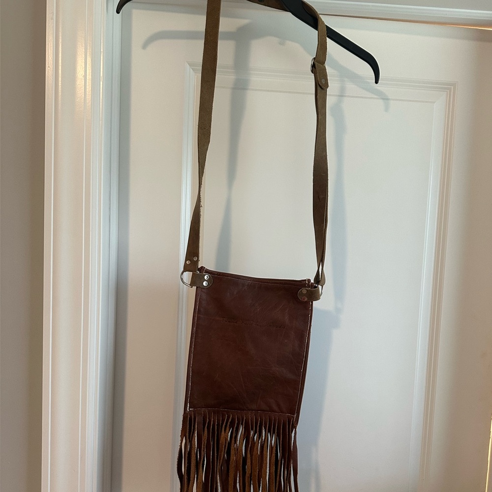 This is a small brown leather fringed bag